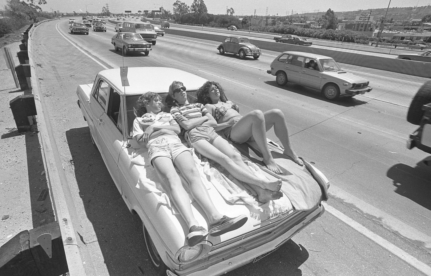 Kids sunbathing on their broken-down car